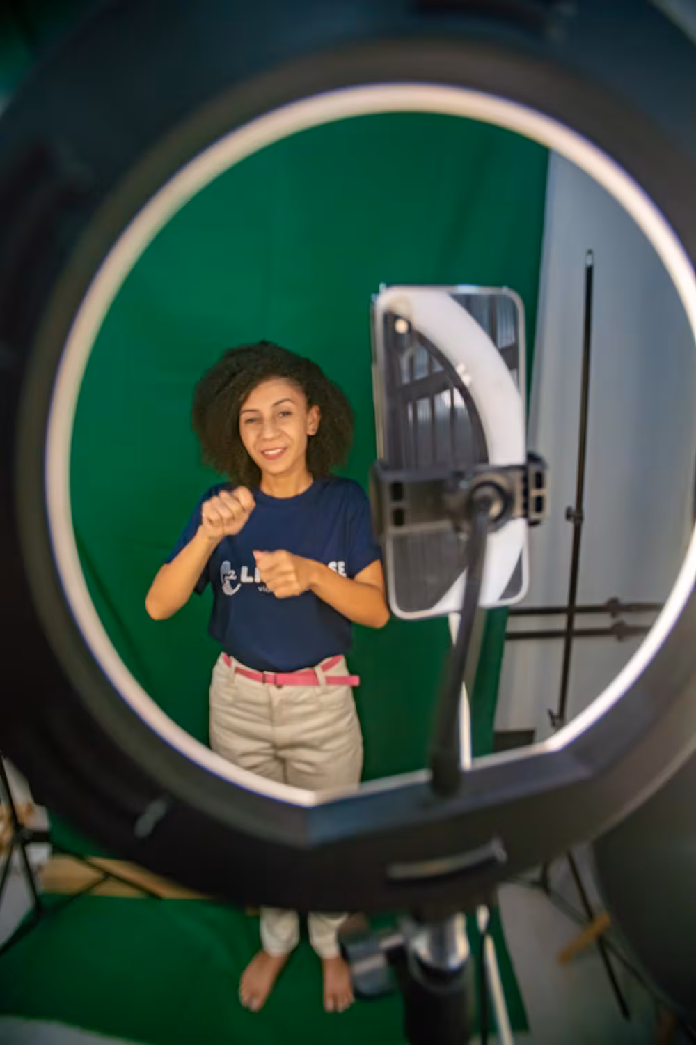 Intérprete de Libras vista através de ring light durante gravação