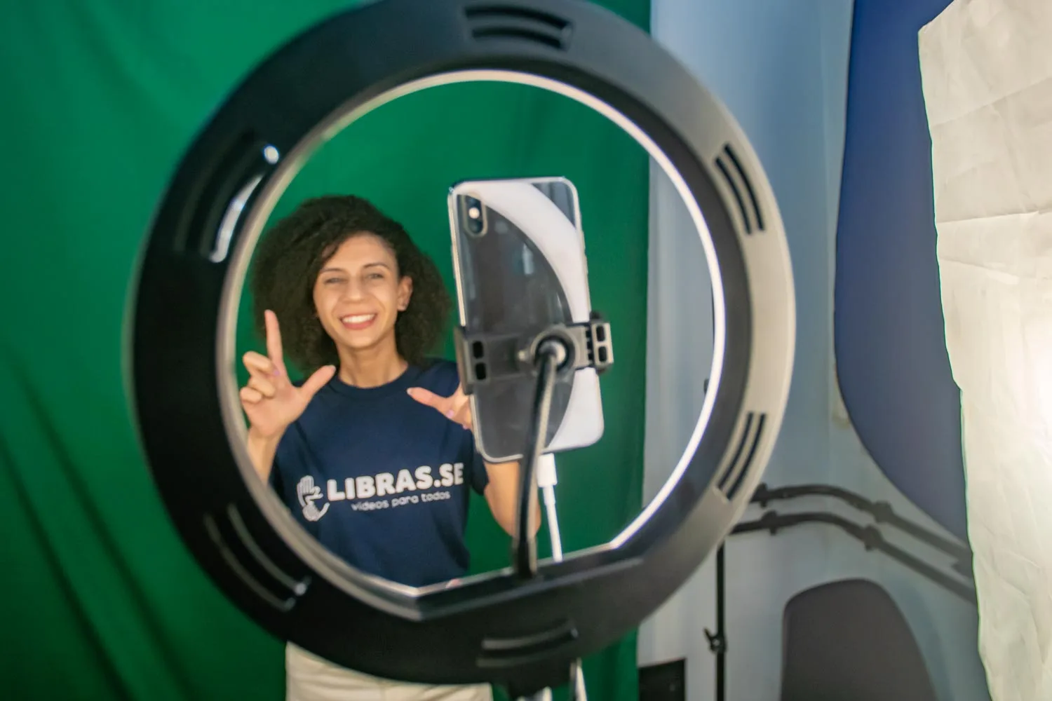 Intérprete de Libras sorrindo durante gravação de videoaula com ring light