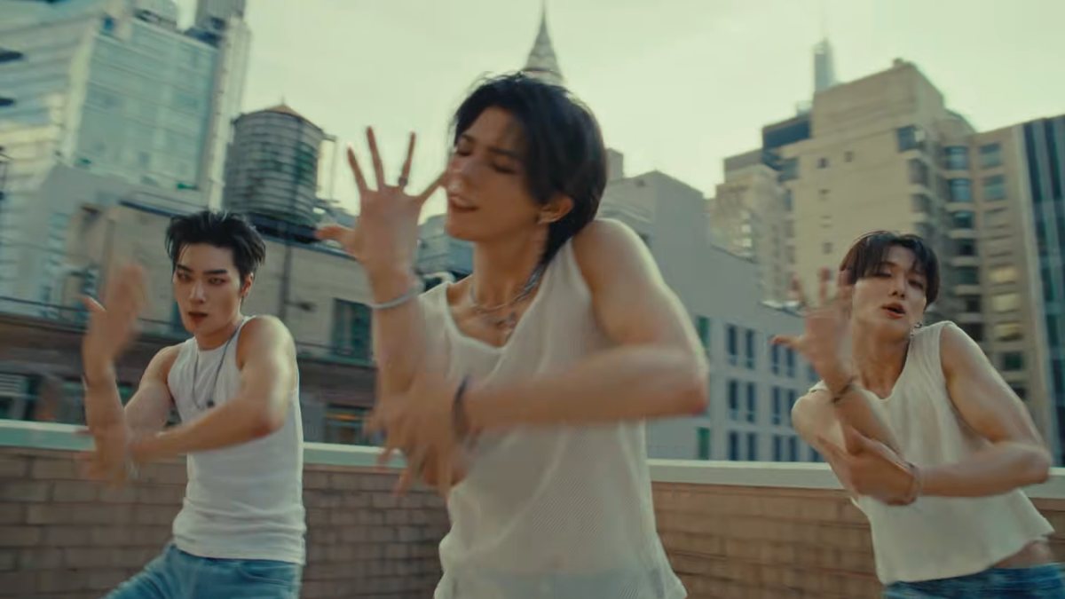 Os três integrantes do Big Ocean dançam num terraço, com prédios ao fundo, no clipe de “Love Sign”