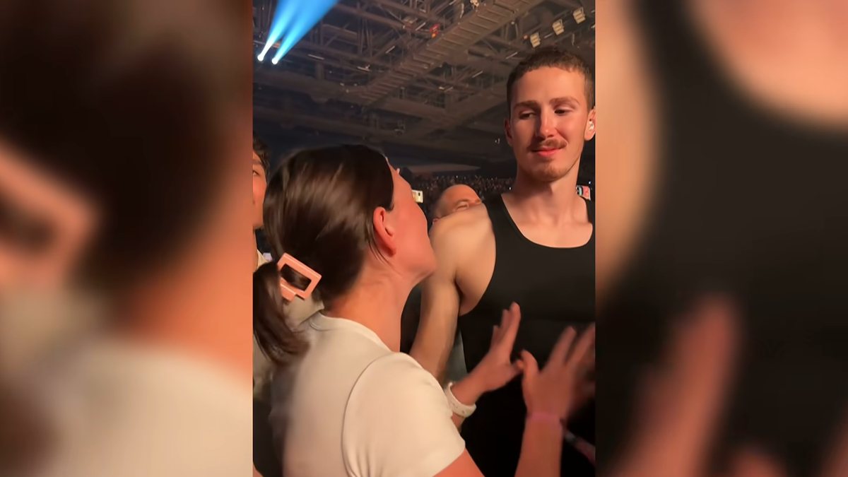 Mikayla Booth sinaliza em Auslan para o namorado, Nyle McQuitty, durante o show de Alex Warren