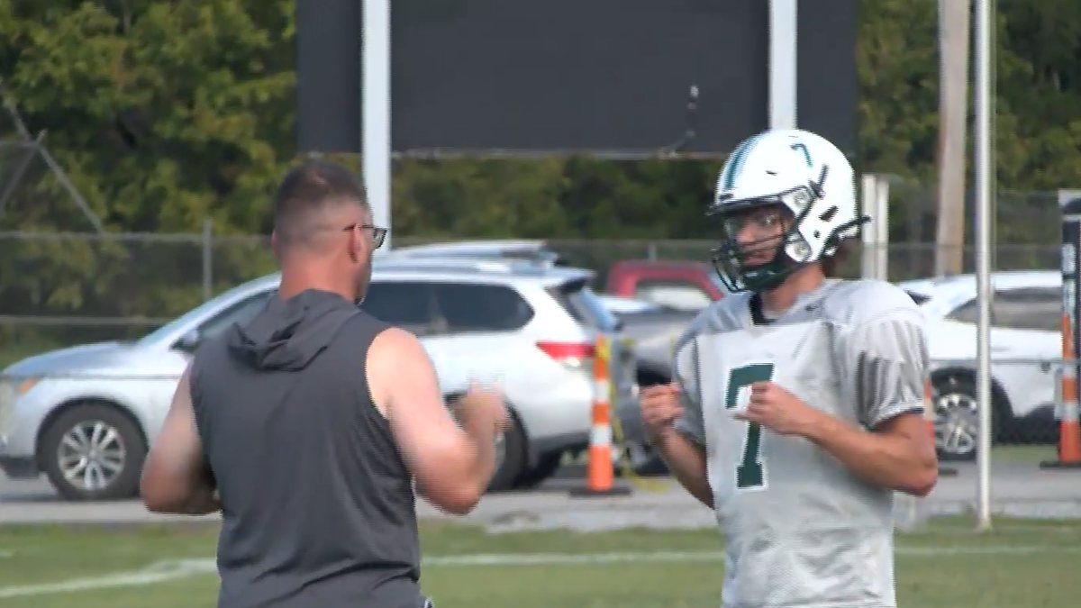 Um dos técnicos conversa com o quarterback Tanner Collins, de capacete e camisa 7, durante o treino